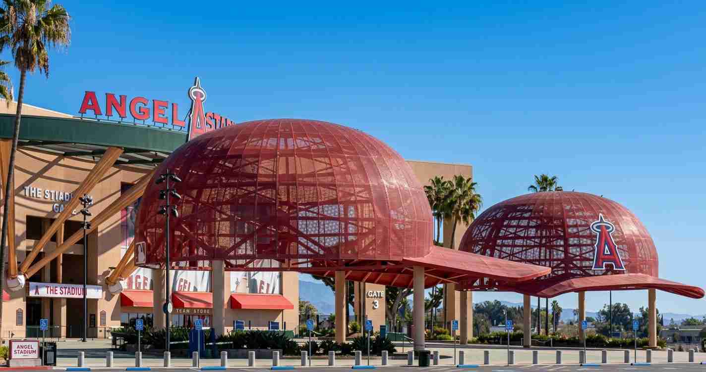 Exterior view of Angel Stadium of Anaheim with two red dome structures and clear blue sky, signage visible above the entrance.