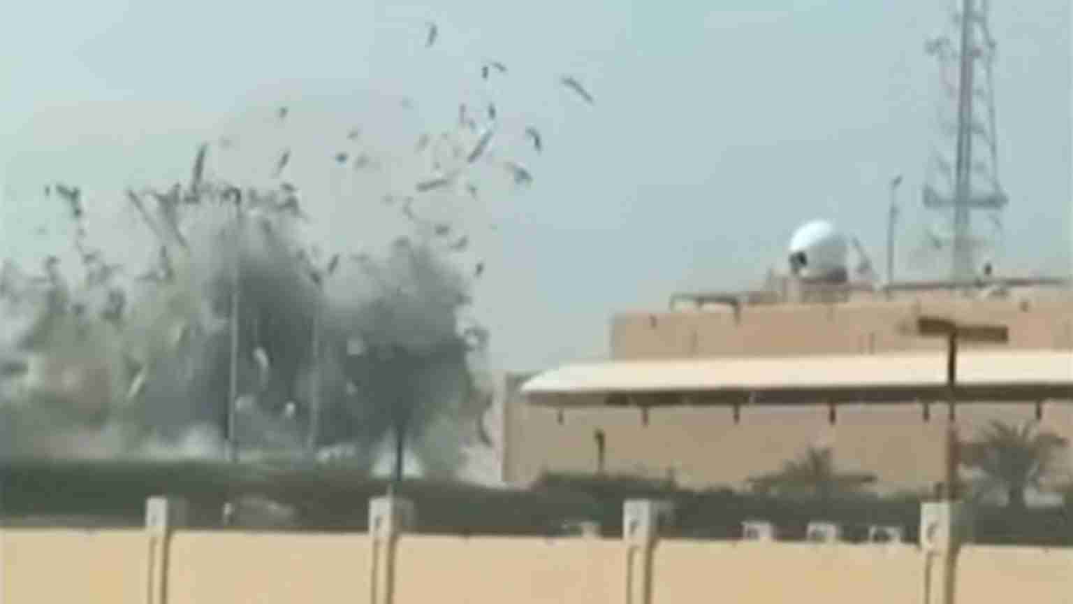 Explosion near a beige military building with a white dome, smoke and debris in the air.