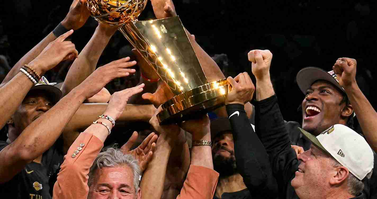 Athletes and fans raise a gleaming trophy in a jubilant victory celebration.