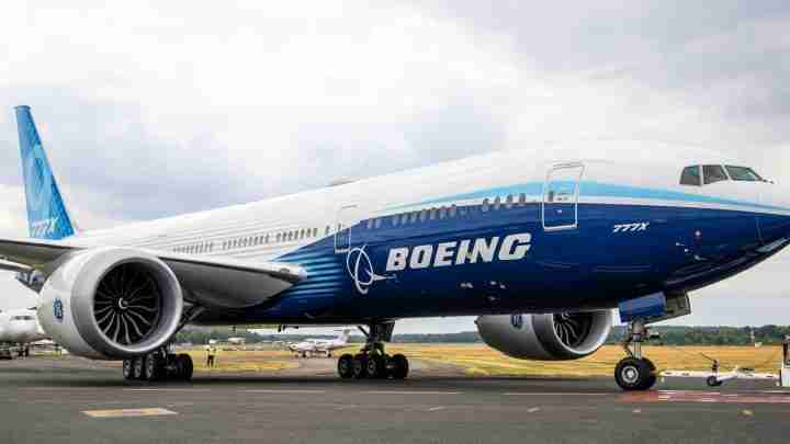 Large Boeing airliner on the tarmac with blue and white livery and visible engines.