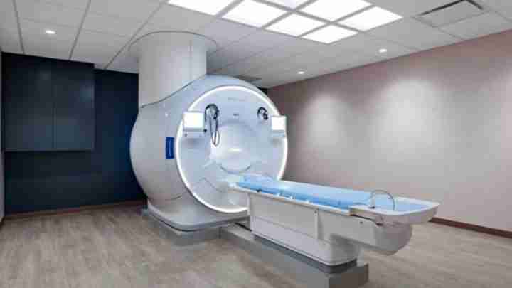 MRI scanner with a circular bore and a patient table extended out in a clinical room