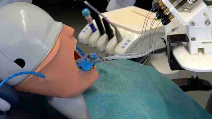 An anesthesia training mannequin with an endotracheal tube connected to a ventilator and monitoring equipment on a clinical setup