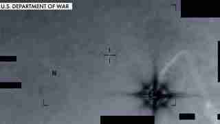 Infrared targeting view with crosshair aiming at a bright explosion plume on the right; label reads 'U.S. Department of War' in the top-left corner.
