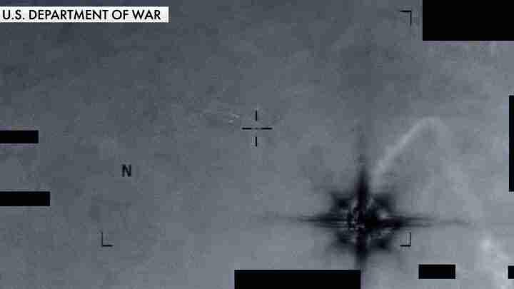 Infrared targeting view with crosshair aiming at a bright explosion plume on the right; label reads 'U.S. Department of War' in the top-left corner.