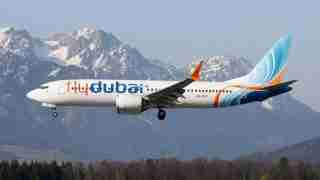 Flydubai passenger jet in flight with snow-capped mountains in the background